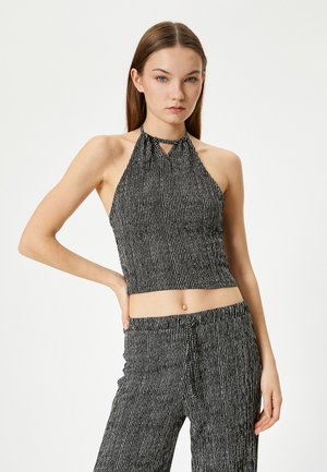 Zwart-witte gestreepte halter crop top met een keyhole halsdetail, een aansluitend ontwerp en een gemarmerde stof. Gepaard met bijpassende gestreepte broek.