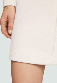 Cremfarbendes Kleid aus weichem, strukturiertem Stoff mit einem gerippten Muster. Verfügt über einen geraden Saum und einen glatten Abschluss an den Ärmeln.