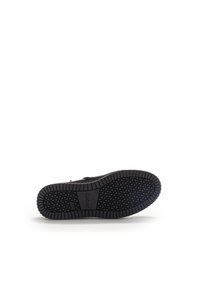 Suela de sneaker de goma negra con un patrón de textura en la banda de rodadura y un logo embosado. Material superior liso visible a lo largo de los bordes. Diseño minimalista.