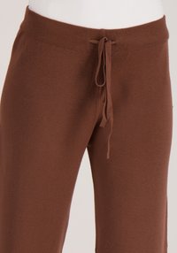 Bruine joggingbroek van zachte stof, met een elastische tailleband en trekkoord en een losse pasvorm. Glad oppervlak met minimale details.