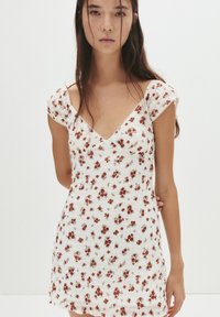 Rochie albă cu flori, cu mâneci scurte, având un design ajustat, textură plisată și un model de flori mici roșii și maronii.