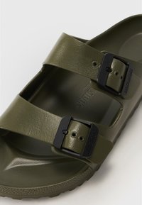Olive green sandal featuring two wide straps with textured surface and contrasting black buckles. Molded footbed and rubber outsole.