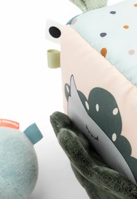 Soft fabric toy cube with polka dots, a smiling face, and tabs in mint green and pale yellow; features a plush character with green felt accents.