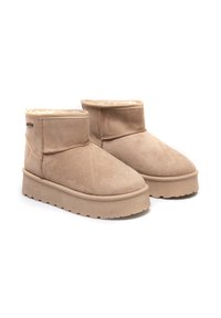 Béžové semišové kotníkové boty s měkkou vnitřní podšívkou, zaoblenou špičkou a silnou, texturovanou podrážkou. Krátká nožka s minimálním prošíváním.