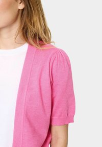 Vaaleanpunainen neuletakki, jossa on lyhyet puffihihat, valmistettu pehmeästä kankaasta. Ominaisuuksiin kuuluu avoin etuosa ja ribattu reunus, joka tuo lisää tekstuuria.