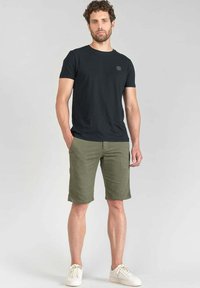 Zwart katoen t-shirt met ronde hals, gecombineerd met groene katoenen shorts. Draag het met witte sneakers, met een eenvoudig, casual ontwerp.