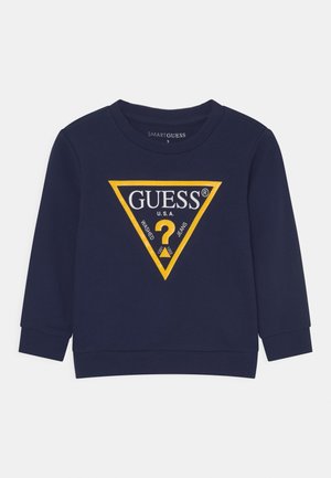Felpa a maniche lunghe blu navy con polsini a costine, dotata di un grande logo triangolare giallo e testo "GUESS U.S.A." sul davanti.