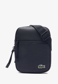 Bolso negro de hombro hecho de tela texturizada. Forma rectangular con un bolsillo con cremallera en la parte frontal, correa ajustable y detalle de logo bordado.