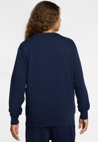 Felpa blu navy con maniche lunghe, polsini e orlo a coste, e collo rotondo. Realizzata in un morbido tessuto testurizzato, senza loghi o motivi visibili.