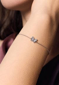 Srebrna bransoletka w kształcie motyla z delikatnym łańcuszkiem, ozdobiona motywem motyla akcentowanym małymi, przezroczystymi kryształkami.