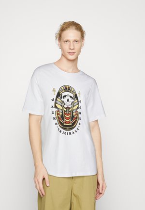 T-shirt en coton blanc avec un graphique d'un squelette portant un couvre-chef de pharaon, rehaussé de rouge et de jaune sur un fond noir.
