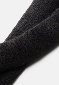 Zwarte gebreide sjaal met een zachte textuur, met een losse weving en een gedraaide ontwerp, dat subtiele variaties in garendikte vertoont.