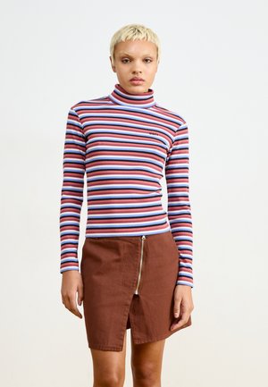 Maglione a collo alto a righe in rosso, blu e rosa, con texture a costine. Abbinato a una gonna marrone con zip frontale e dettaglio slit.