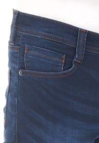 Dżinsy w ciemnoniebieskim kolorze z pomarańczowymi szwami, z boczną kieszenią i lekko zwężanym krojem. Tkanina wydaje się gładka z subtelną teksturą.