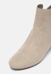 Bottine en daim beige avec bout rond et finition lisse, vue avant supérieure et latérale sur fond blanc.