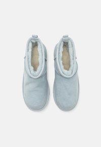 Botines de ante azul claro sin cordones con suave forro de piel sintética color crema, punta redondeada y detalles cosidos alrededor de la abertura.