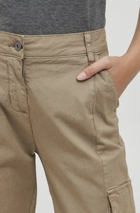 Beige cargo bukser lavet af letvægtsstof, med sidelommer, knaplukning og løs pasform. Synlige syninger på stoffet.