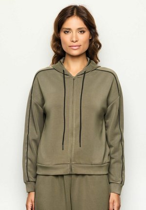 Sudadera con cremallera en verde oliva con cordones, que presenta acentos laterales en negro, un ajuste relajado y una tela suave y texturada.
