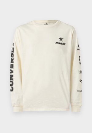 Gräddvit långärmad t-shirt med svart Converse-stjärnlogotyp och text på bröstet samt tryckt märkning vertikalt och horisontellt på båda ärmarna.