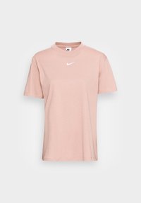 Ljust rosa bomullströja med korta ärmar, rundad halsringning och en liten vit Nike-logotyp i mitten. Enkelt, odekorerat mönster.