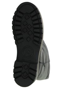 Semelle de chaussure noire en caoutchouc avec un motif de grip texturé et un logo circulaire. La partie supérieure présente un design en tissu gris avec des détails cousus.