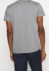 Šedé tričko s krátkým rukávem vyrobené z jemné tkaniny, s klasickým kulatým výstřihem a jednoduchým designem, s mírně zakřiveným lemem.