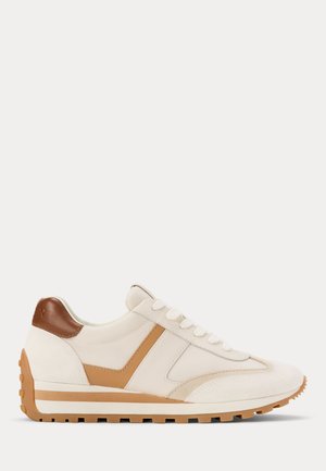 Beige en bruine lage sneaker met witte veters, een getextureerde zool en een bruine hielpatch, weergegeven in zijaanzicht op witte achtergrond.