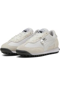 Bílé tenisky s svrchním materiálem z semišu a textilu, kulatou špičkou a černou gumovou podrážkou. Obsahují branding PUMA na jazyku a boku. Klasický design.