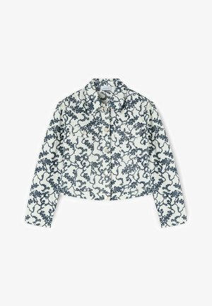 Chaqueta blanca recortada con un patrón de enredadera floral negra, mangas largas, botones al frente y cuello puntiagudo.