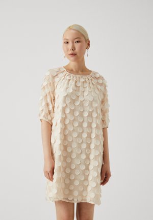 Short, light beige dress with a round neckline and short sleeves, featuring a textured pattern of raised polka dots throughout.