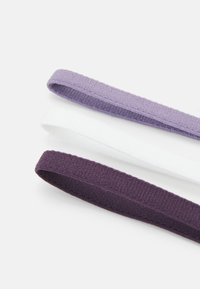Trys elastingos plaukų gumelės šviesiai violetinės, baltos ir tamsiai violetinės spalvų. Kiekviena gumelė turi minkštą audinio tekstūrą ir plokščią, apvalią formą.