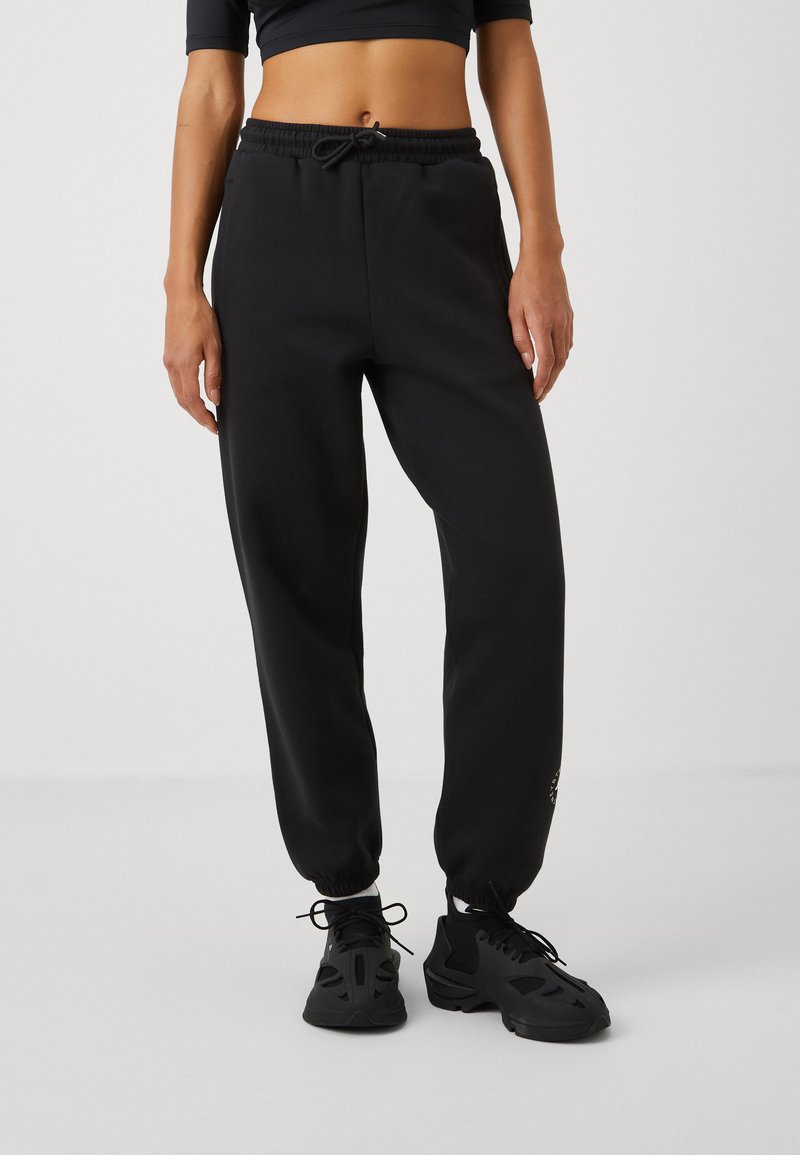 Black sweatpants with an elastic waistband and drawstring, featuring tapered cuffs and a subtle logo on the left leg.
