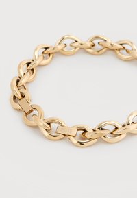 Βραχιόλι αλυσίδας σε χρυσό τόνο με οβάλ κρίκους και κούμπωμα χαραγμένο με τη λέξη "BOSS" σε ανοιχτό φόντο.