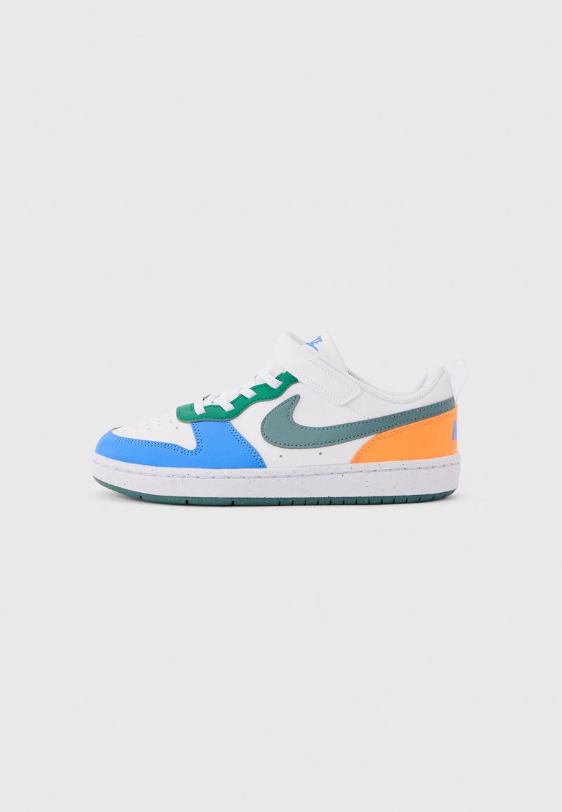 Baskets blanches avec des panneaux bleus, verts et orange, un swoosh Nike gris et une sangle velcro sur un fond gris clair.