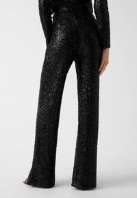 Schwarze Paillettenhose mit weitem Bein, glatter Textur und hoch tailliertem Design mit dezentem Schimmer.