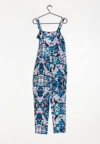 Combinaison fleurie avec bretelles ajustables, présentant un mélange de motifs bleus, violets et verts sur un fond sombre, le tissu est lisse et léger.