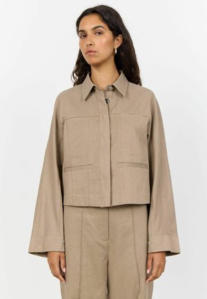 Gekürzte beigefarbene Jacke aus einem weichen Stoff, mit einer Knopfverschließung, zwei vorderen Taschen und weiten Ärmeln mit Bündchen.
