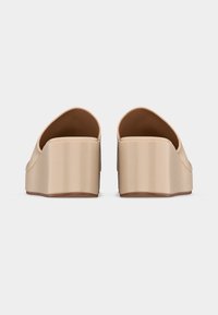 Μπεζ πλατφόρμα πλατφόρμες με σφήνα, που φαίνονται από πίσω, με λείο υλικό και κλειστή φτέρνα.