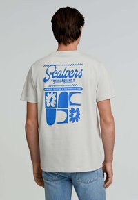 Light gray cotton t-shirt featuring a blue graphic design on the back with floral and abstract shapes, and the text "Scalpers | The Skull Brand."