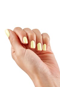 Uno smalto giallo chiaro ricopre unghie ben sagomate su una mano dal texture liscia, mostrando un aspetto naturale e semplice.