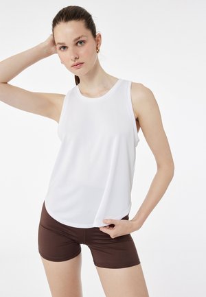 Witte mouwloze sporttop met een ronde hals, gemaakt van lichtgewicht stof. Gepaard met bruin aansluitende shorts, met een gladde textuur.