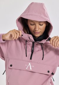 Rosa Pullover-Hoodie mit Kapuze, ausgestattet mit einem Reißverschluss vorne, schwarzen Kordeln mit einem gemusterten Griff und einer Fronttasche mit Logo-Details.