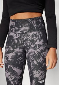 Sort og grå mønstrede leggings med høj talje, lavet af struktureret stof, har et hvidt logo på det nederste ben.