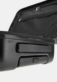 Black hard-shell suitcase with smooth texture, zippered compartments, and sturdy gray accents. Opens to reveal a black fabric interior.