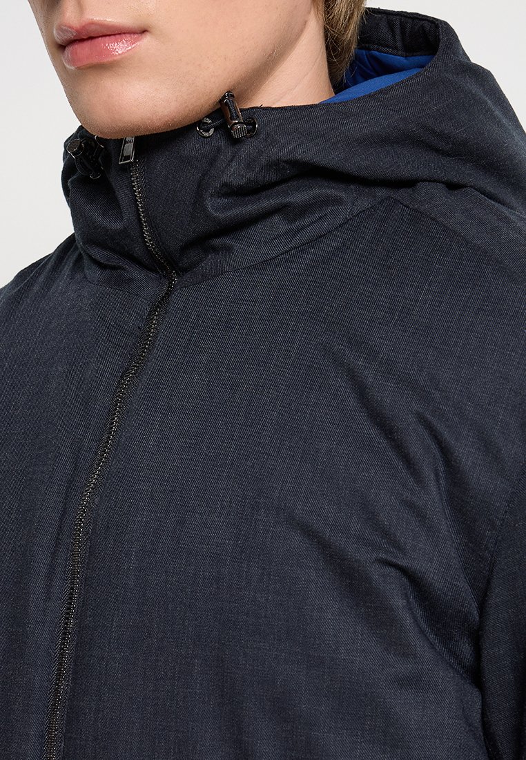 Veste noire zippée avec col haut et capuche. Présente une texture lisse, un éclat subtil et une doublure intérieure bleue contrastante.