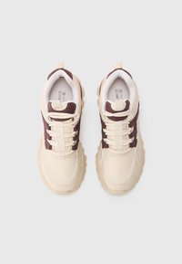 Pair of beige and dark brown chunky sneakers with thick soles and lace-up design viewed from above on a plain white background.