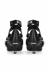 Chaussures à talons hauts noires avec un bout pointu, en cuir, dotées de brides à la cheville avec des éléments métalliques argentés, et une surface élégante et lisse.