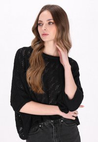 Maglione nero a maglia con una vestibilità ampia, scollatura rotonda a costine e maniche a tre quarti; presenta un motivo in pizzo e un tessuto texturizzato.