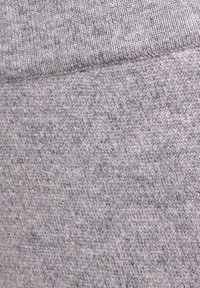 Grijs gebreide stof met een zachte textuur, met een licht gemêleerd patroon. De weving is gelijkmatig en consistent over het materiaal.