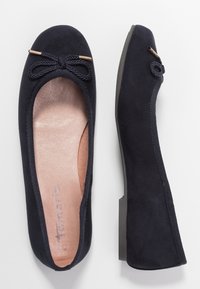 Ein Paar schwarze Wildleder-Balletschuhe mit Schleifendetail an der Zehenpartie und hellbraunen Innensohlen, von oben und von der Seite auf weißem Hintergrund gezeigt.